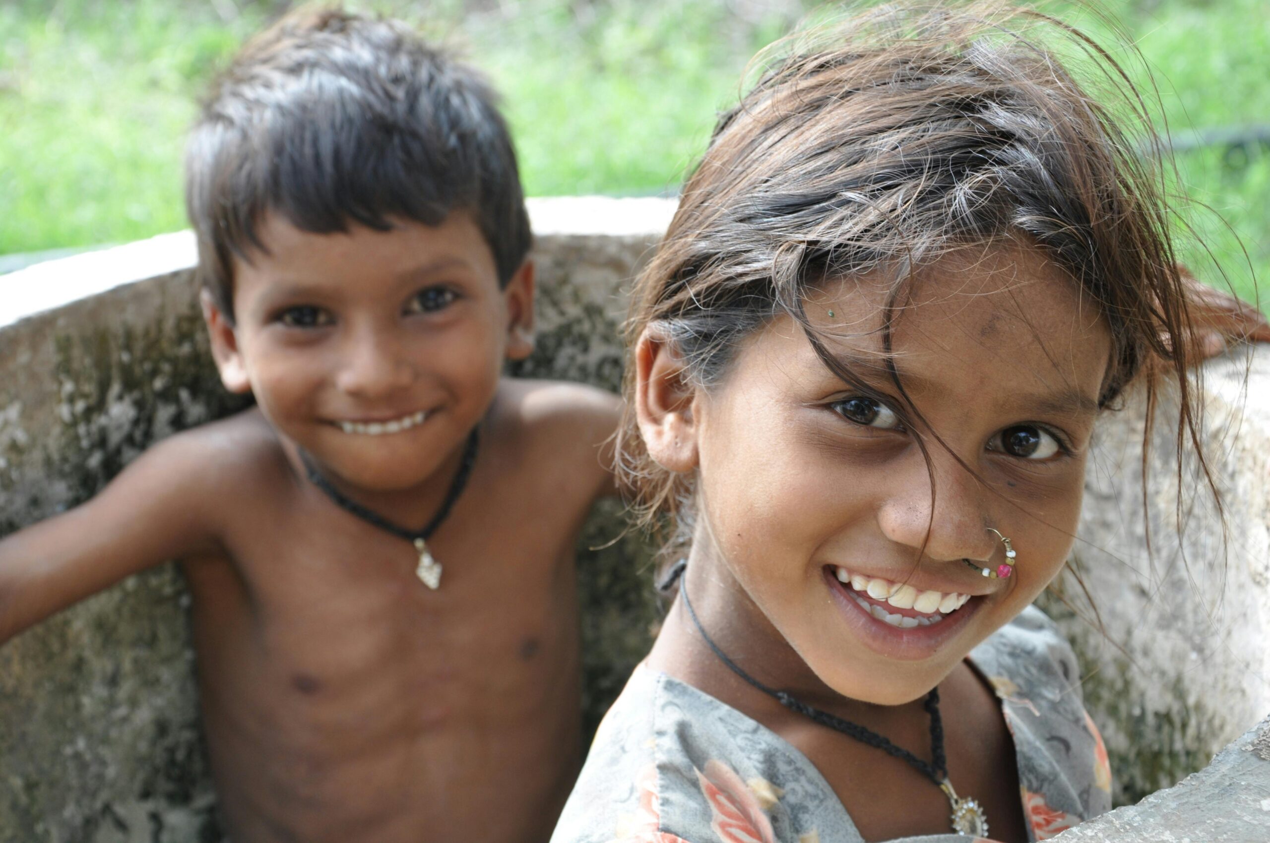 Two smiling children enjoying a sunny day outside, capturing innocence and joy.