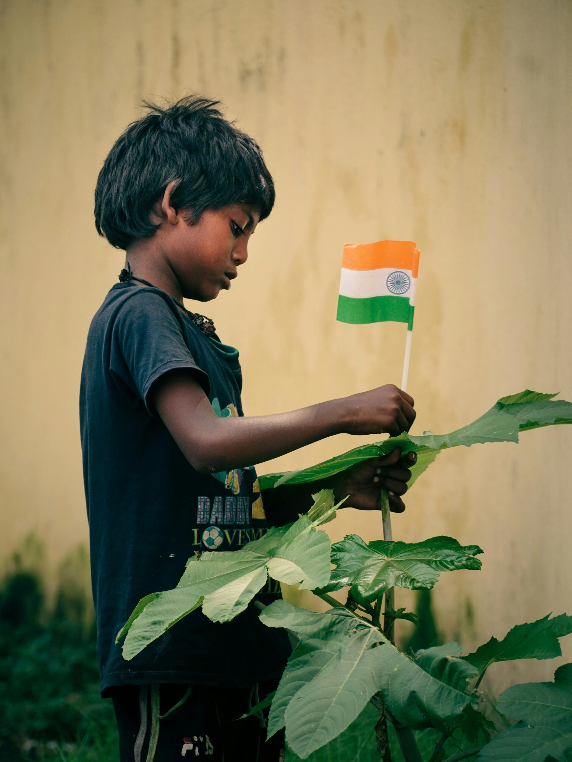 A young boy holds an Indian flag in a garden setting, symbolizing patriotism in Asansol, India.